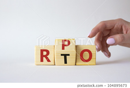 RPO vs RTO symbol. Businessman hand points at wooden cubes with words RTO and RPO. Beautiful white background. business concept. Copy space 104895673