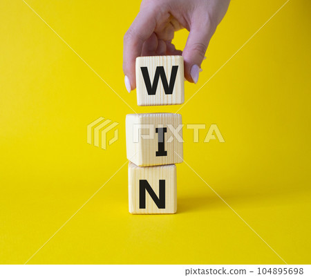 Win symbol. Wooden blocks with words Win. Businessman hand. Beautiful yellow background. Business and Win concept. Copy space. 104895698