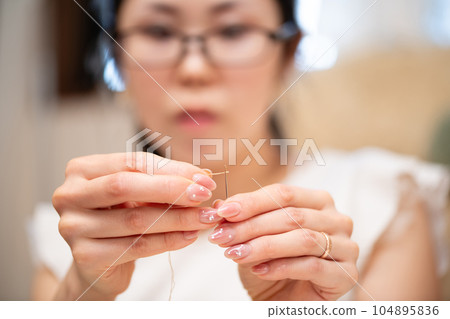 一個女人通過針穿過一根針 104895836