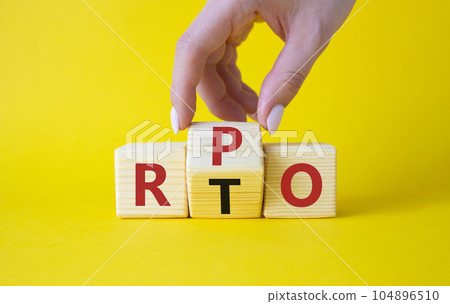 RPO vs RTO symbol. Businessman hand turns wooden cubes and changes the word RTO to RPO. Beautiful yellow background. business concept. Copy space RPO vs RTO symbol. Businessman hand turns wooden cubes and changes the word RTO to RPO. Beautiful yellow background. business concept. Copy space 104896510