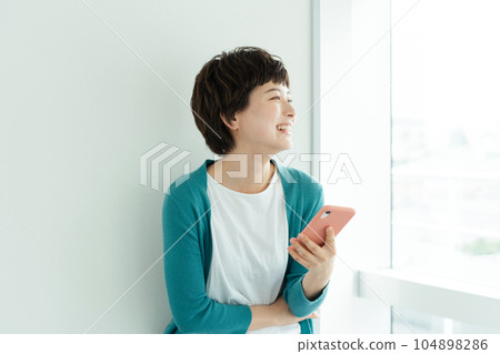 A young woman operating a smartphone 104898286