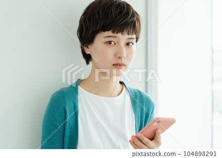A young woman operating a smartphone A young woman operating a smartphone 104898291