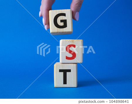 GST - Goods and Services Tax symbol. Concept word GST on wooden cubes. Businessman hand. Beautiful blue background. Business and GST concept. Copy space. GST - Goods and Services Tax symbol. Concept word GST on wooden cubes. Businessman hand. Beautiful blue background. Business and GST concept. Copy space. 104898641