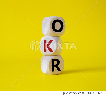 OKR objectives and key results symbol. Wooden cubes with words OKR objectives and key results. Beautiful yellow background. Business and OKR concept. Copy space. OKR objectives and key results symbol. Wooden cubes with words OKR objectives and key results. Beautiful yellow background. Business and OKR concept. Copy space. 104898670