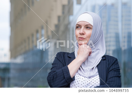 Portrait of pensive business woman in hijab and suit outdoors. Portrait of pensive business woman in hijab and suit outdoors. 104899735