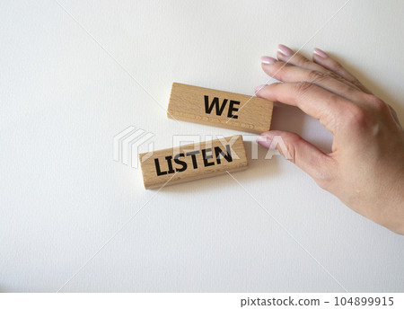 We listen symbol. Wooden blocks with words We listen. Businessman hand. Beautiful white background. Business and We listen concept. Copy space. We listen symbol. Wooden blocks with words We listen. Businessman hand. Beautiful white background. Business and We listen concept. Copy space. 104899915