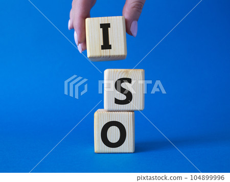 ISO standards quality control symbol. Concept word ISO on wooden cubes. Businessman hand. Beautiful blue background. Business and ISO concept. Copy space. ISO standards quality control symbol. Concept word ISO on wooden cubes. Businessman hand. Beautiful blue background. Business and ISO concept. Copy space. 104899996