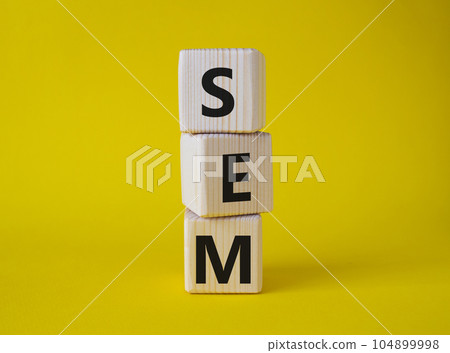 SEM - Search Engine Marketing symbol. Wooden cubes with words SEM. Beautiful yellow background. Business and SEM concept. Copy space. 104899998