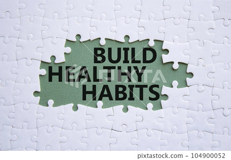 Healthy habits symbol. Concept word Build Healthy habits on white puzzle. Beautiful grey green background. Healthy lifestyle and Healthy habits concept. Copy space Healthy habits symbol. Concept word Build Healthy habits on white puzzle. Beautiful grey green background. Healthy lifestyle and Healthy habits concept. Copy space 104900052
