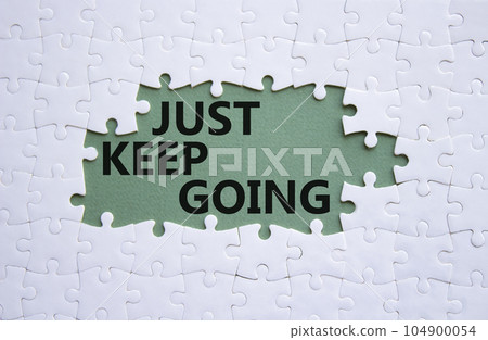 Just keep going symbol. White puzzle with words Just keep going. Beautiful grey green background. Business and Just keep going concept. Copy space. Just keep going symbol. White puzzle with words Just keep going. Beautiful grey green background. Business and Just keep going concept. Copy space. 104900054