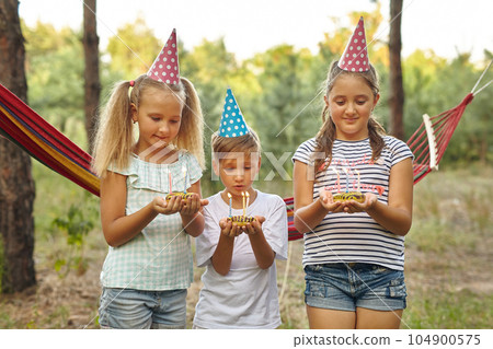Children holding birthday cakes with burning candles. 104900575