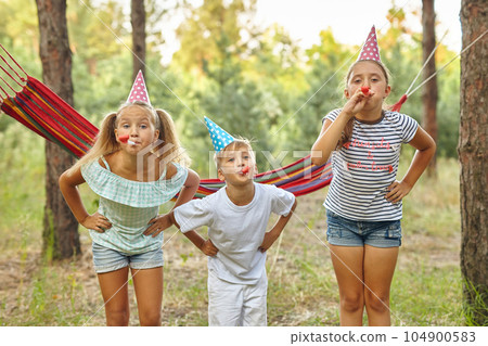 happy kids blowing party horns and having fun in summer outdoors 104900583