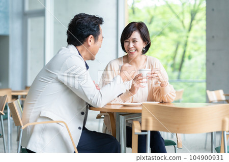 A couple drinking coffee and having a conversation in a cafe 104900931