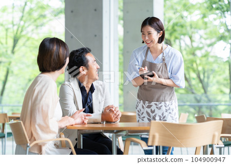 A clerk serving a middle-aged couple at a cafe A clerk serving a middle-aged couple at a cafe 104900947