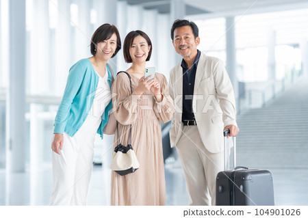 A middle-aged couple and their daughter's family traveling while operating a smartphone A middle-aged couple and their daughter's family traveling while operating a smartphone 104901026