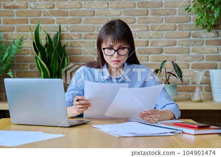 Middle-aged business woman office worker, manager working with business papers 104901474