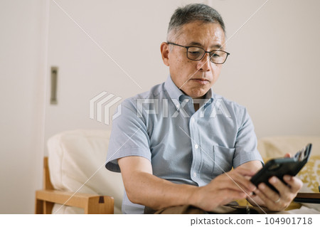 戴著老花鏡和眼鏡並操作智能手機的男人 104901718