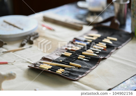 Various tools for pottery on table in workshop. Handicraft, creativity, hobby and activity concept Various tools for pottery on table in workshop. Handicraft, creativity, hobby and activity concept 104902156