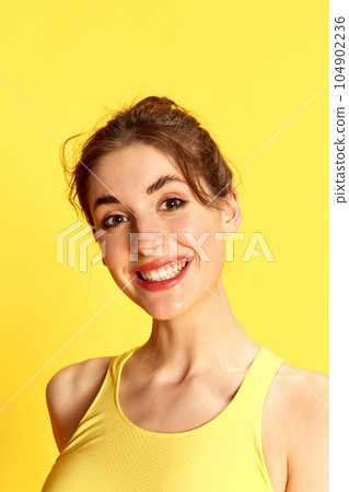 Portrait of beautiful young woman cheerful smiling, posing against yellow studio background. Positive mood Portrait of beautiful young woman cheerful smiling, posing against yellow studio background. Positive mood 104902236