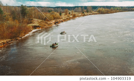 Men Dressed As US American Soldiers Of USA Infantry Of World War II carry out rafting on rubber boats In spring Autumn Day. Group of Soldiers people are preparing to disembark. Aerial view elevated 104903319