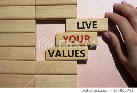 Live your values symbol. Concept words 'Live your values' on wooden blocks. Beautiful pink background. Businessman hand. Business and Live your values concept. Copy space. Live your values symbol. Concept words 'Live your values' on wooden blocks. Beautiful pink background. Businessman hand. Business and Live your values concept. Copy space. 104903791