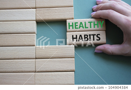 Healthy habits symbol. Concept word Healthy habits on wooden blocks. Businessman hand. Beautiful grey green background. Business and Healthy habits concept. Copy space 104904384