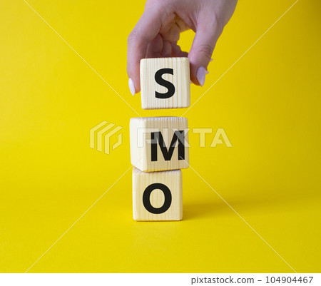 SMO - Social Media Optimization symbol. Wooden blocks with words SMO. Businessman hand. Beautiful yellow background. Business and SMO concept. Copy space. SMO - Social Media Optimization symbol. Wooden blocks with words SMO. Businessman hand. Beautiful yellow background. Business and SMO concept. Copy space. 104904467