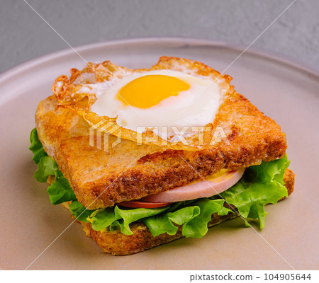 fried egg on sandwich with sausage on plate 104905644