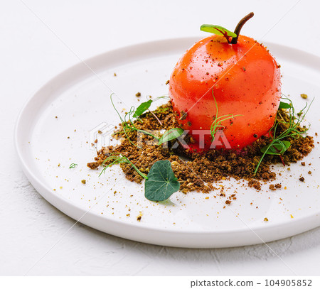 unusual dessert in the shape of a tomato on a white plate unusual dessert in the shape of a tomato on a white plate 104905852