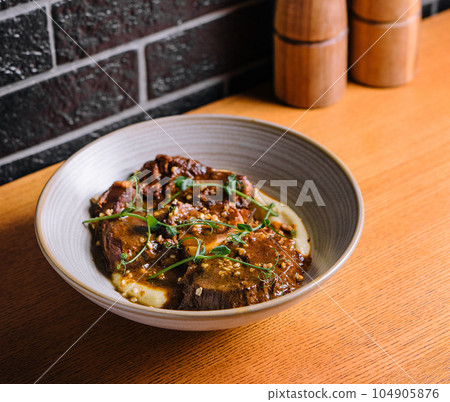 Traditional german braised veal cheeks in brown sauce with mashed potatoes Traditional german braised veal cheeks in brown sauce with mashed potatoes 104905876