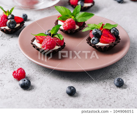 Chocolate ganache tarts with fresh berries 104906051