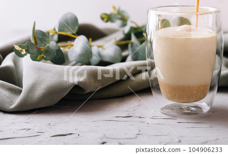 pouring a coffee with milk from teapot to glass cup pouring a coffee with milk from teapot to glass cup 104906233