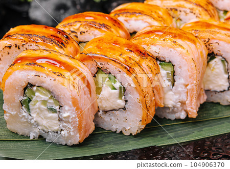Rolls with fried salmon and cheese, cucumber on plate 104906370