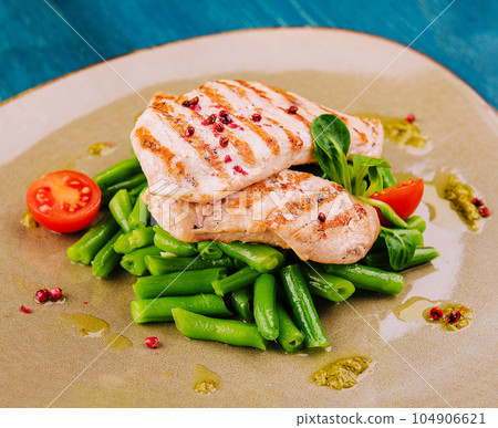 Grilled chicken fillets on green beans 104906621