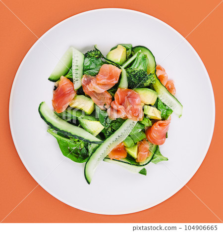 Salmon avocado salad with salted fish, lettuce, broccoli and cucumbers 104906665