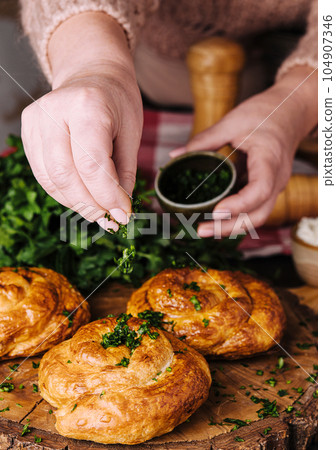 woman sprinkles dill fresh on twisted bun woman sprinkles dill fresh on twisted bun 104907346