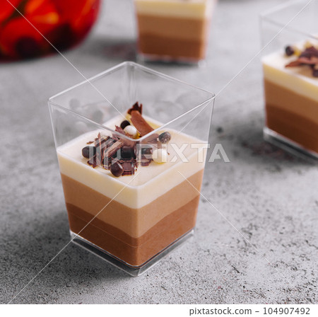 Layered dessert Trifles in a transparent glasses 104907492