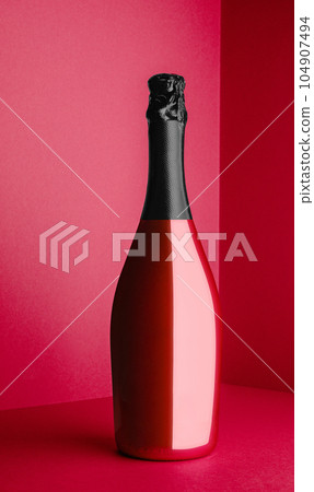 red Champagne bottle on light red background 104907494