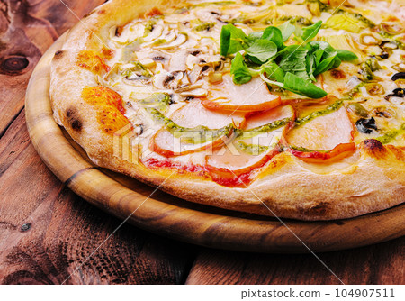 Pizza with ham and mushrooms on a wooden board 104907511
