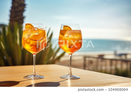 Two glasses with a cocktail and an orange with ice on the table Two glasses with a cocktail and an orange with ice on the table 104908004
