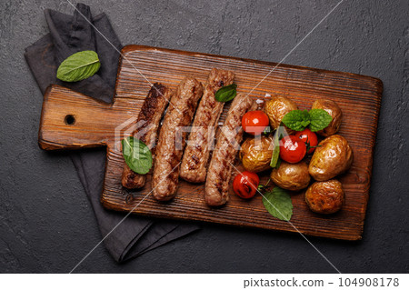 Delicious grilled sausages and potatoes Delicious grilled sausages and potatoes 104908178