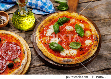 Margarita and pepperoni pizza with tomatoes, mozzarella cheese and basil Margarita and pepperoni pizza with tomatoes, mozzarella cheese and basil 104908222