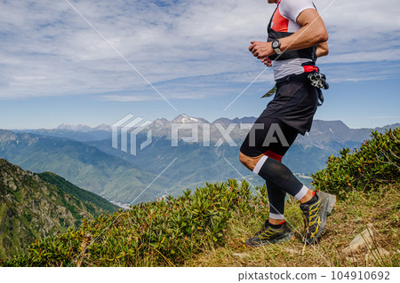 male athlete running from mountainside in compression sleeves on his feet in mountain marathon race male athlete running from mountainside in compression sleeves on his feet in mountain marathon race 104910692