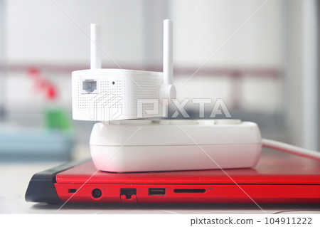 Internet signal booster in a socket, an Internet signal amplifier lies on a laptop, freelancer. 104911222