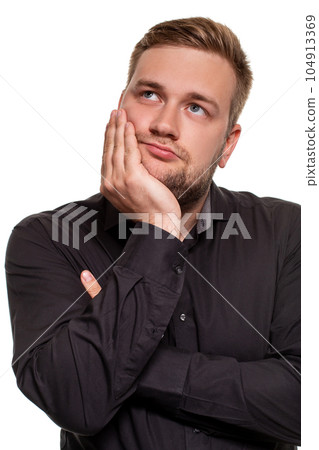Studio portrait of gloomy european man showing boredom while leaning head on hand and standing over white background. 104913369