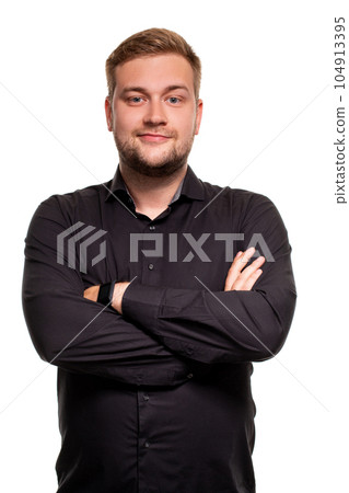 Young man in black shirt is smiling and crossed his arms over chest against white background Young man in black shirt is smiling and crossed his arms over chest against white background 104913395