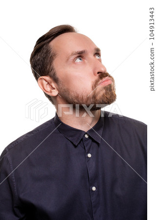 Portrait of a handsome, unshaven man, dressed in a dark blue shirt, standing against a white background. Self confident man. Portrait of a handsome, unshaven man, dressed in a dark blue shirt, standing against a white background. Self confident man. 104913443