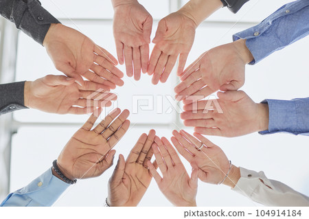 young volunteers putting their hands on top of each other like a real team while standing in charitable organization office 104914184