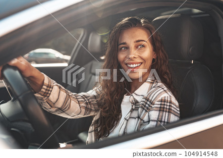 Portrait of a beautiful smiling woman in a car looking out of the window Portrait of a beautiful smiling woman in a car looking out of the window 104914548