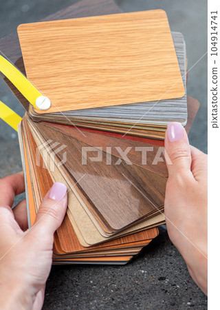 Samples of laminate in the hands of the designer. Selection of samples of laminate flooring. Samples of the floor with imitation wood of different species in the hands, close-up. Samples of laminate in the hands of the designer. Selection of samples of laminate flooring. Samples of the floor with imitation wood of different species in the hands, close-up. 104914741